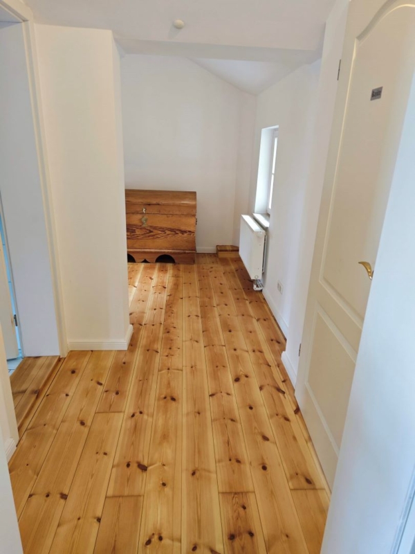 Flur mit Holzboden, weißen Wänden und einer Holztruhe